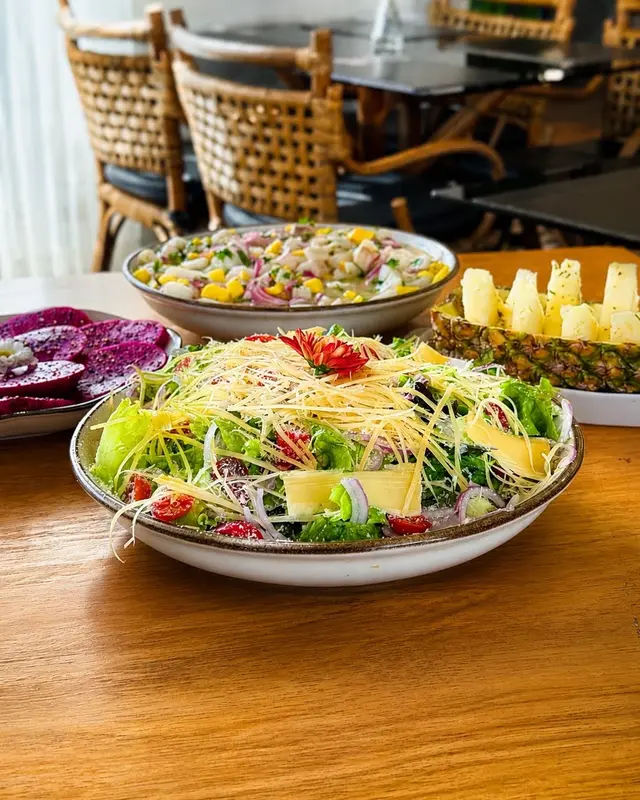 Salada contemporânea com lâminas frescas e flores comestíveis sobre cerâmica artesanal
